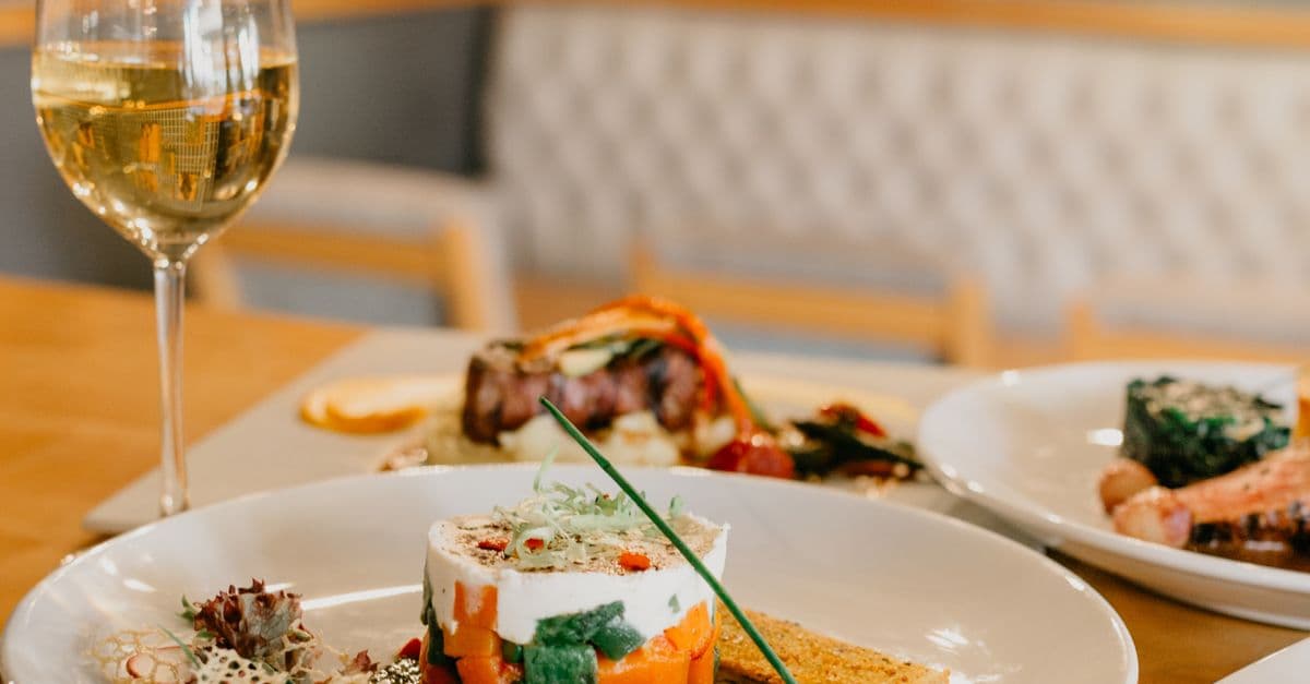 Gedeckter Restauranttisch mit mehreren Gerichten und Weißwein