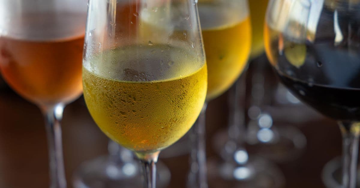 Mehrere Gläser mit Weißwein, Rotwein und Rosé auf einem Holztisch